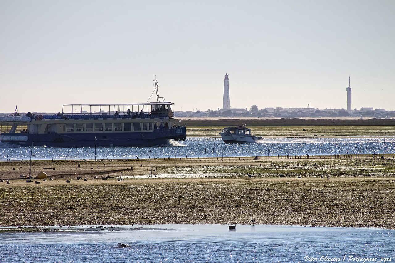 Laguna Ria Formosa przy Olhão w odpływ: łachy, kanały i statek na wyspy.