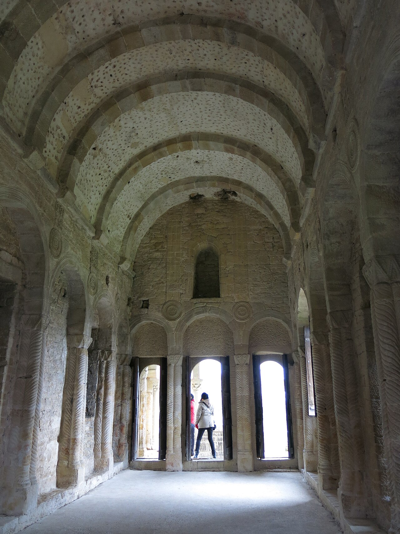 Górna sala Santa María del Naranco: sklepienie z łukami poprzecznymi, kolumny o skręconych trzonach, w głębi loggia z potrójną arkadą